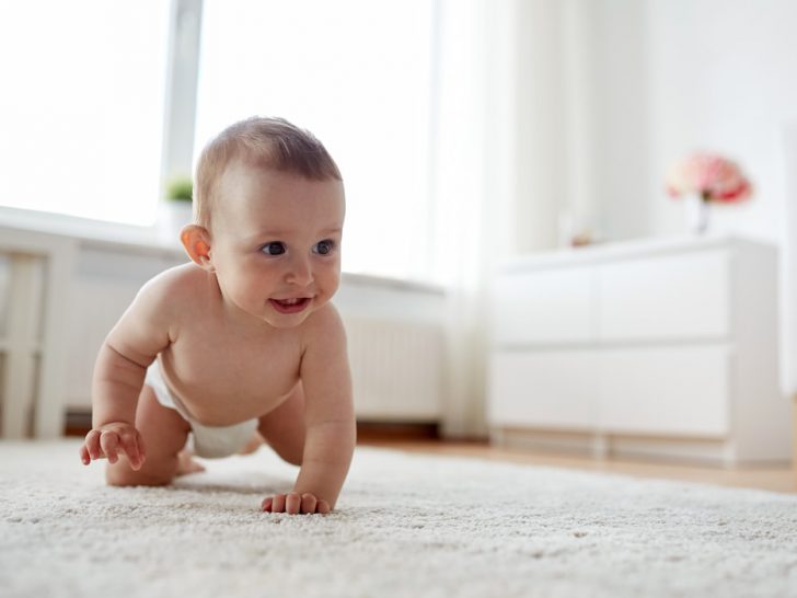little baby in diaper crawling on floor at home