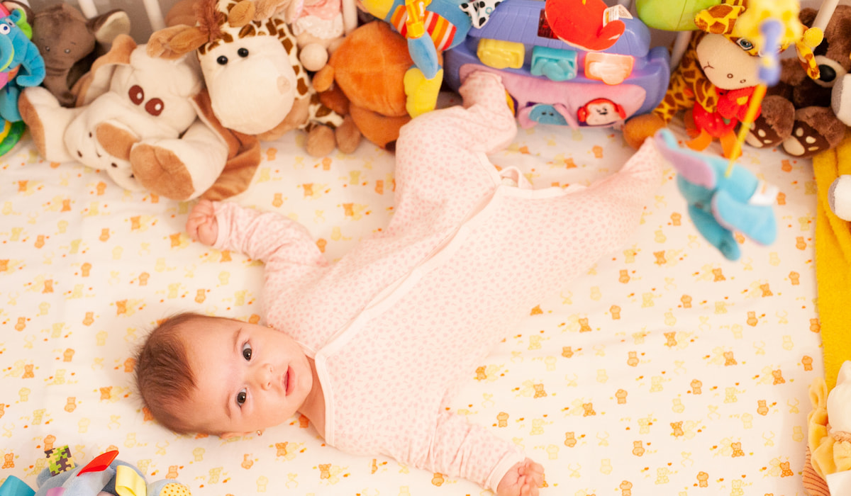 A baby girl in a crib with many toys