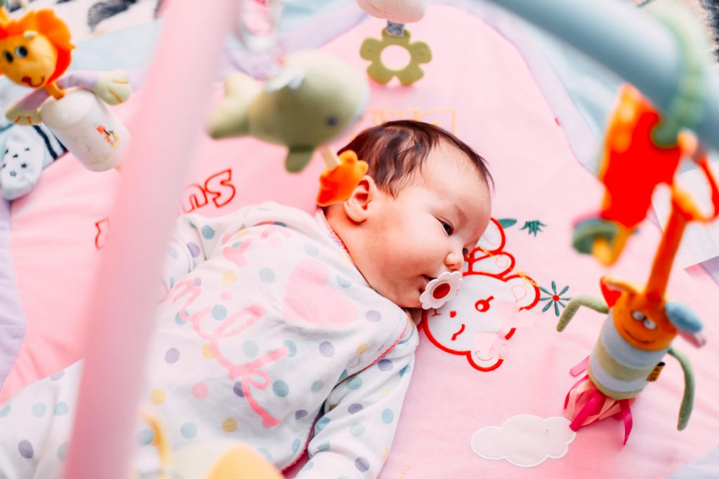 Baby lying on colorful baby play mat with toys