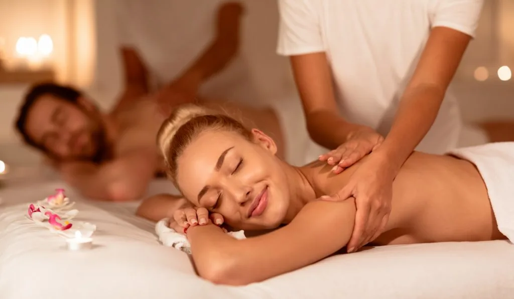 Happy Couple Relaxing Lying In Spa Receiving Back Massage