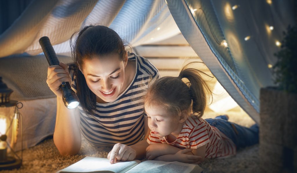Mom and child reading book during bed time 
