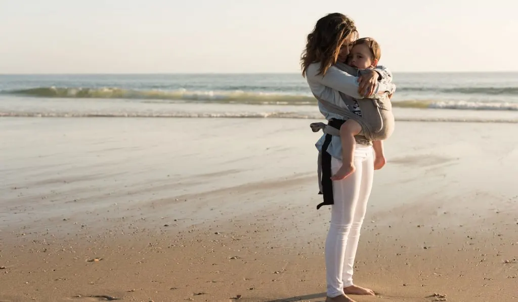 Mother carrying baby on the beach