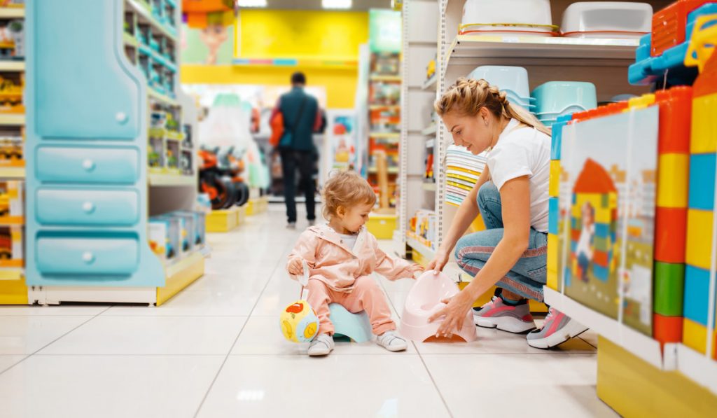 Mother with girl choosing baby potty in kids store