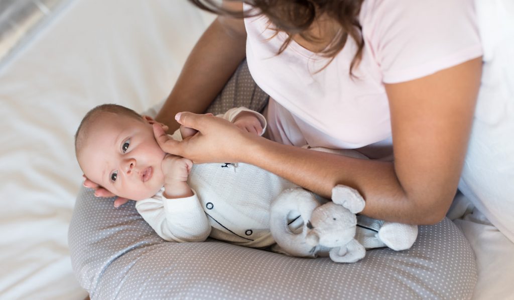 Mother with newborn baby on boppy pillow 
