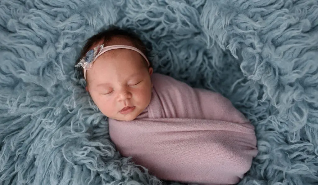 Portrait of a sleeping newborn baby in blue fur