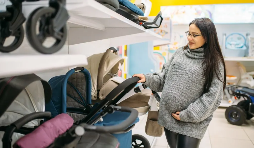Pregnant woman in shop of equipment for newborns