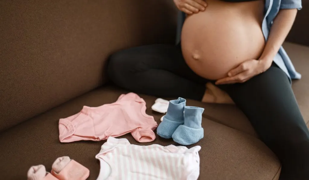 Pregnant woman prepares clothing for newborn 