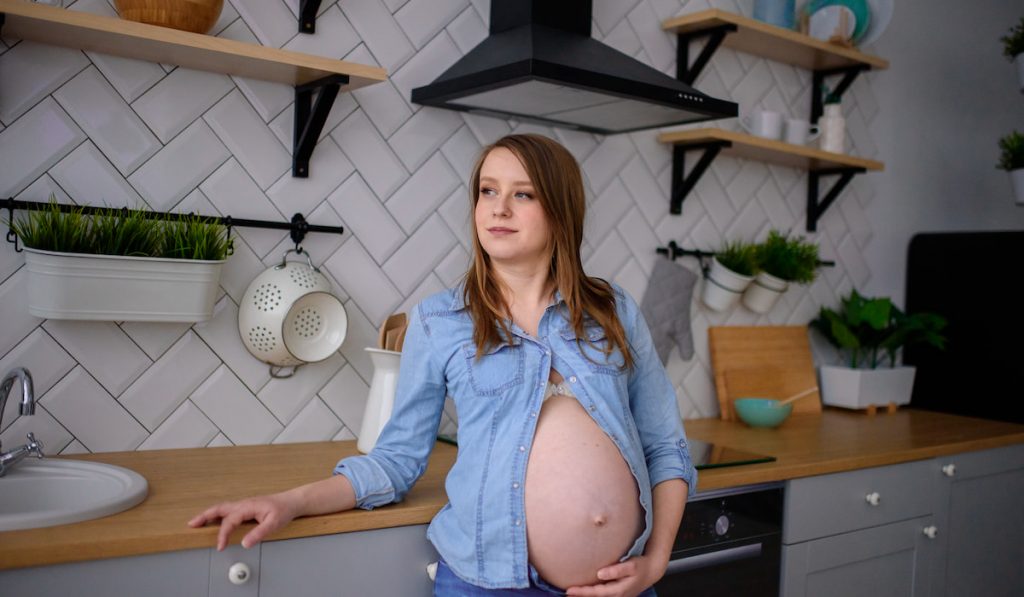 Pregnant woman standing in her kitchen