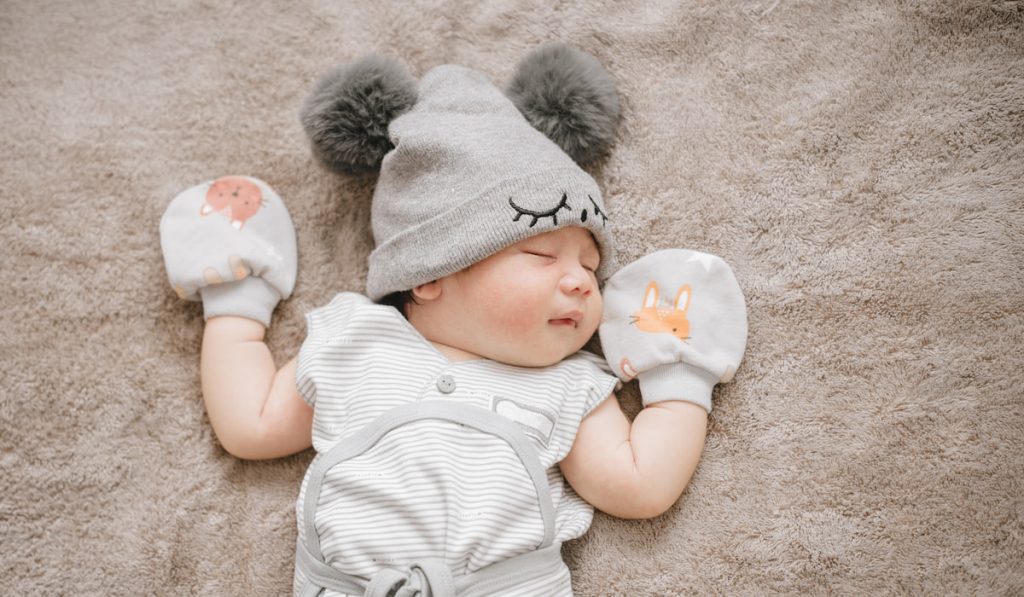 Sleeping baby with hat and mittens 
