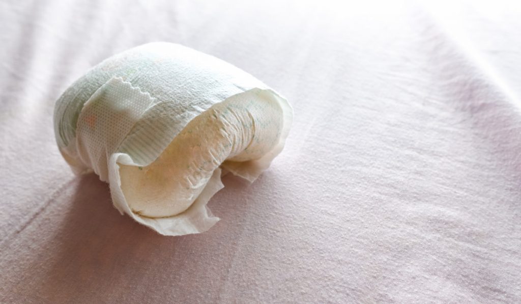 Used diaper of a baby on the bed.
