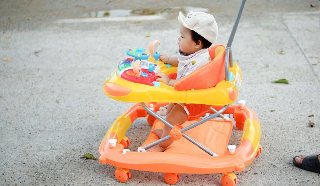 baby in the yard in yellow and orange walker 