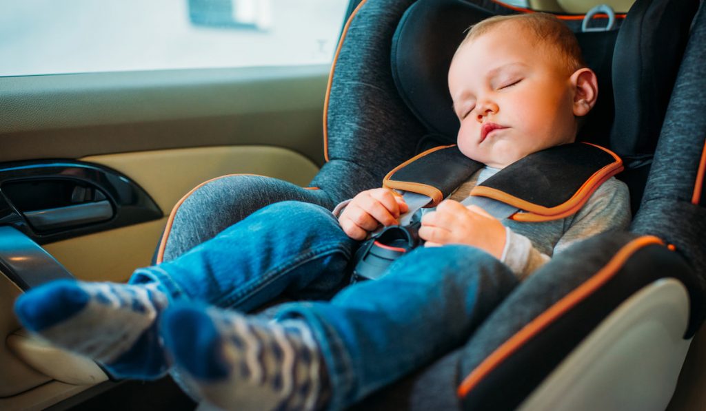 cute little baby sleeping in child safety seat in car