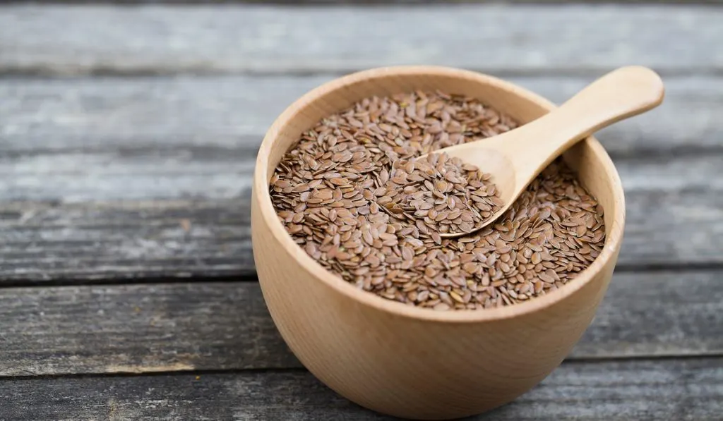 flax seeds in wooden bowl and a wooden spoon 