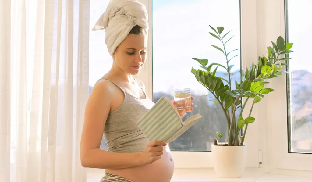 happy pregnant woman reading inspiring book