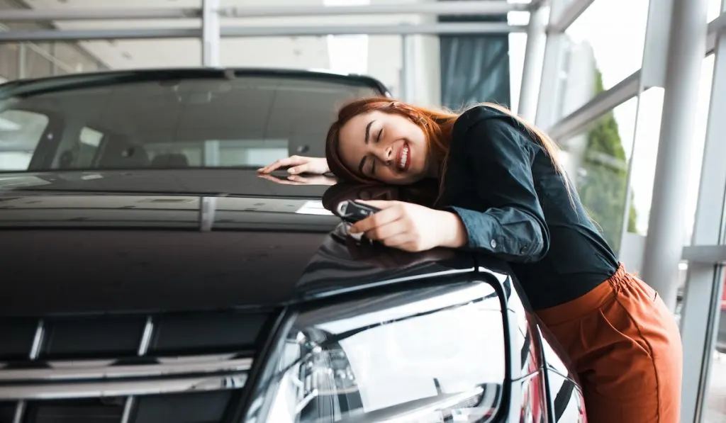 happy woman hugging her new car