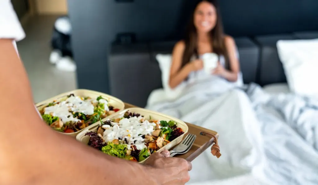 pregnant woman having her prepared breakfast in bed by her husband