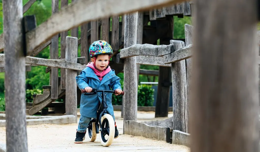 little boy riding a balance bike on the playground
