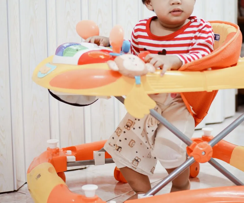 cropped photo of little boy sitting in a walker 