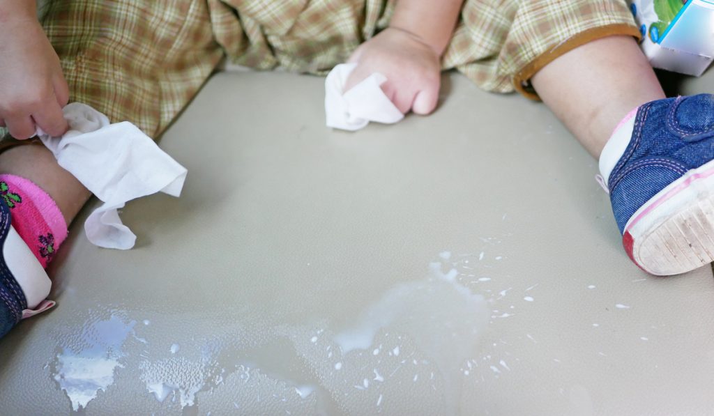 milk poured on car seat baby holding wipes 
