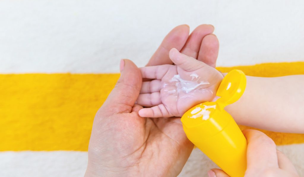 mommy holding baby's hands putting some sunscreen