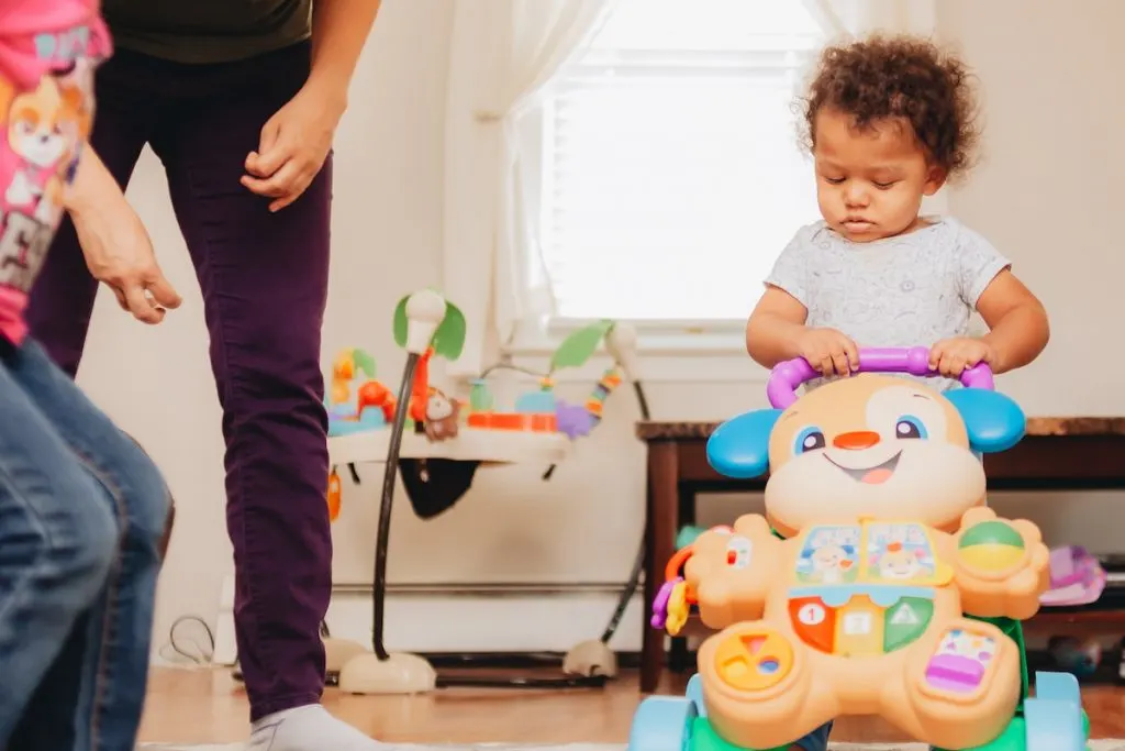 mother and daughter watching baby using training walker -