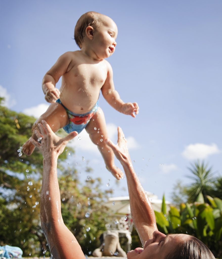 mother throwing her baby in the air enjoying swimming time