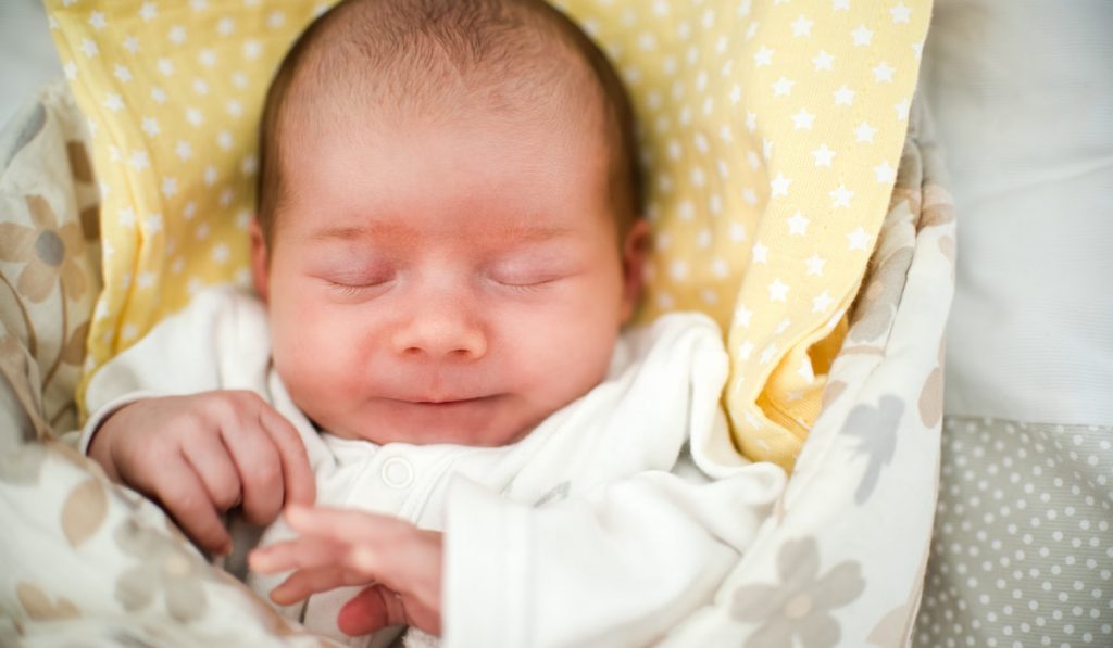 newborn baby sleeping in swaddle wrap 