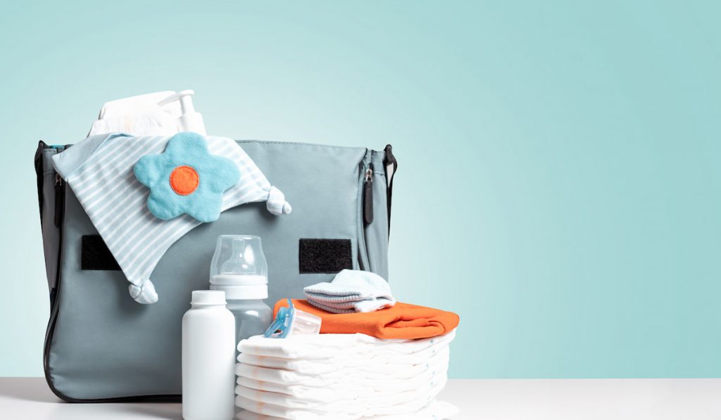 newborn essentials diaper clothes bottle powder and blue bag