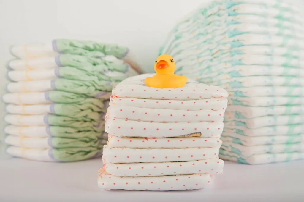 pile of baby diapers and toy duck on white background