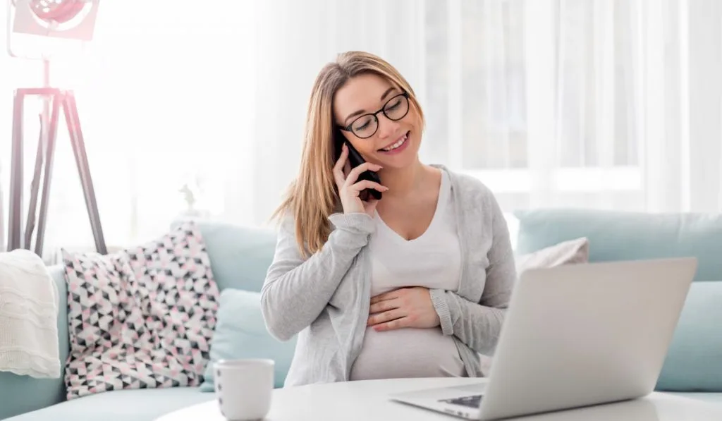 pregnant woman on her phone sitting on the couch 