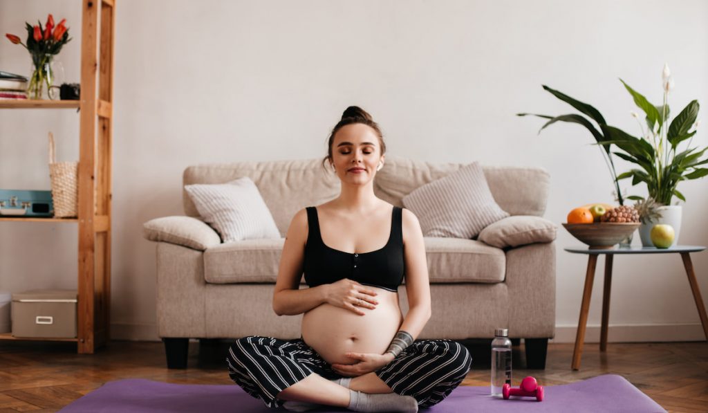 pregnant woman relaxing and enjoying music while touching her belly 