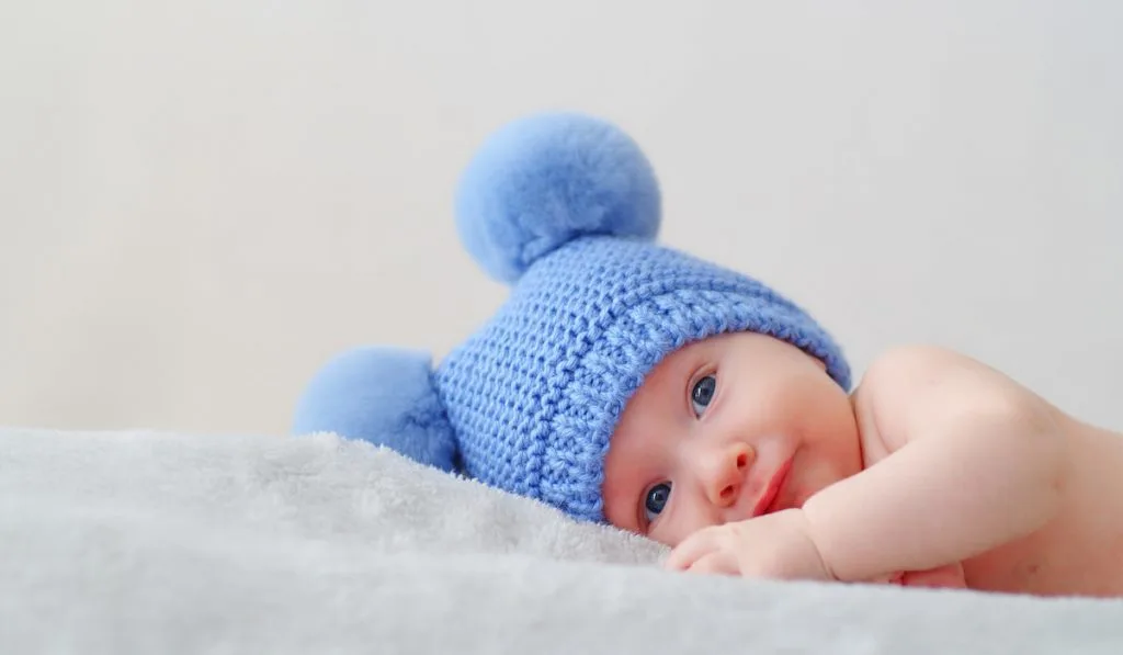 resting cute little infant with blue eyes wearing blue beanie 
