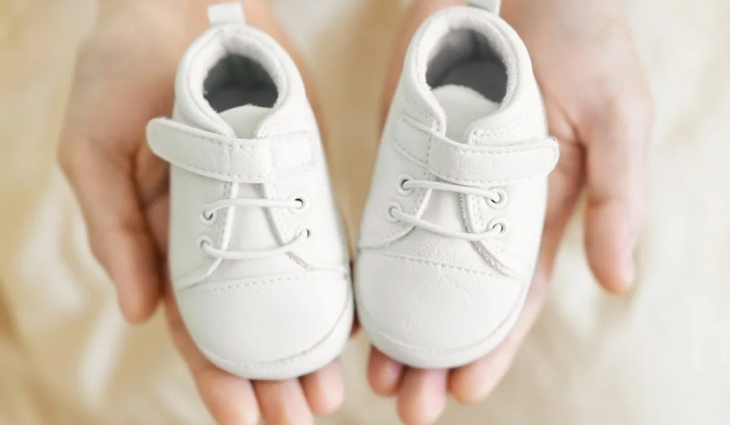 white newborn soft shoes on hand of a man 