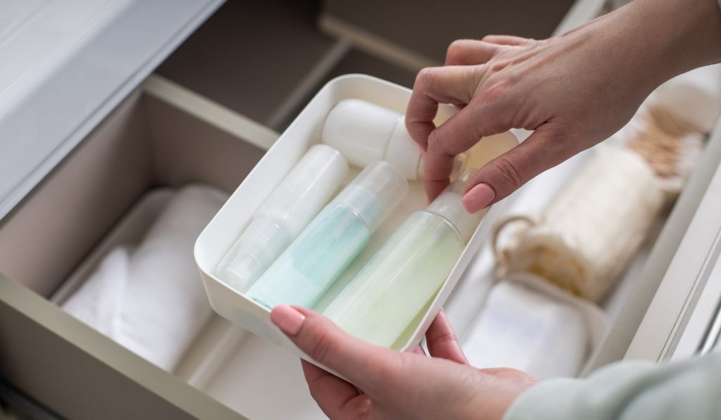 woman preparing and getting toiletries product in open drawer 