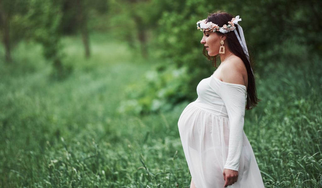 Beautiful pregnant woman in dress have a walk outdoors