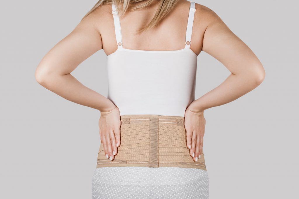 new mom wearing belly brace or band back view, to help remove her postpartum belly 