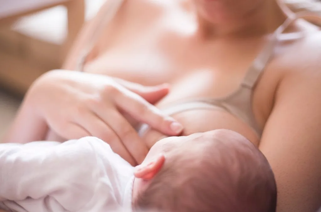 Young mother using nursing bra and breastfeeding her baby