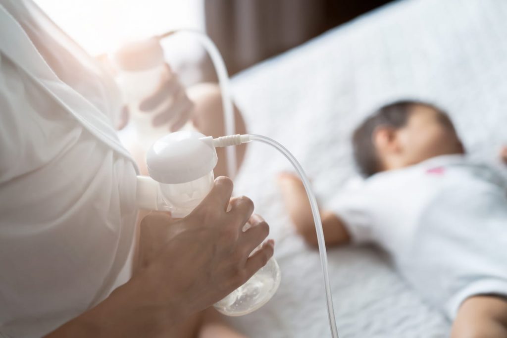 mother pumping breast milk while baby is sleeping